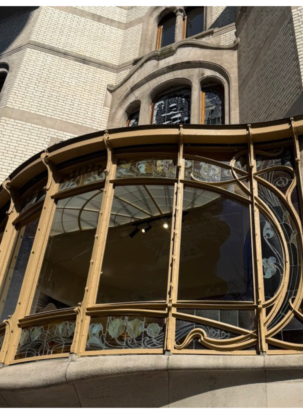 Curved Art Nouveau bay window with wrought-iron mullions and stained glass, Brussels